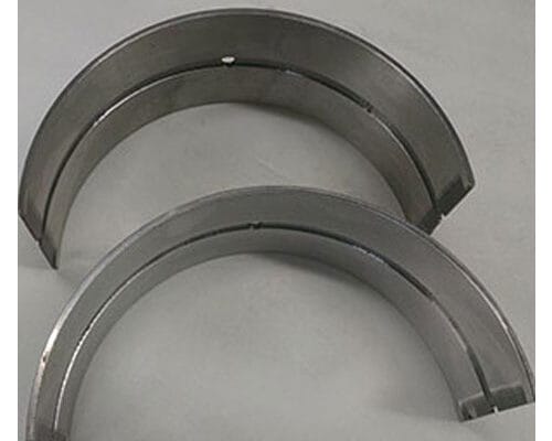 Two steel black aluminum lined bearings against white flat surface.